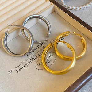 Close-up of brushed gold and silver hoop earrings in a minimalist jewelry display box.