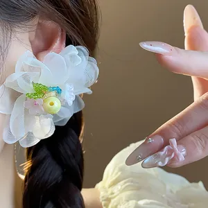 Macro detail of a large white chiffon flower earring with colorful bead accents