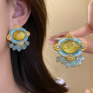 Detailed macro view of vintage oval earrings featuring blue enamel and yellow resin