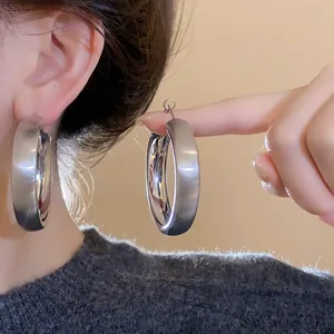 Macro view of minimalist brushed silver circular hoop earrings with a polished interior