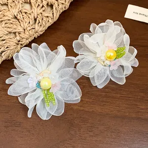 Detailed macro view of white chiffon flower earrings with yellow pearl center and beads