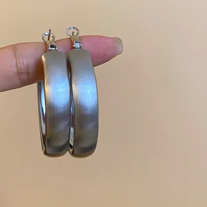 Close-up showing the elegant brushed metal texture of these minimalist silver hoop earrings