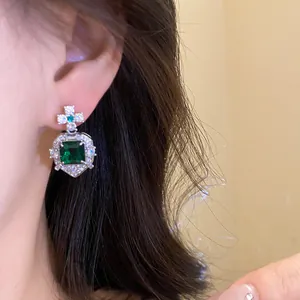 Detail shot of vintage style earrings with square green gemstone and crystals