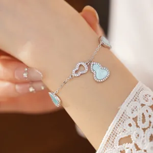 Detailed view of elegant blue hulu charms and zircon hollowed bracelet on a female wrist.