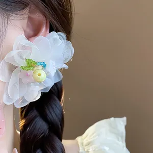 Detailed close-up of white chiffon flower stud earrings with colorful beads on ear