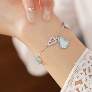 Elegant silver-toned chain bracelet with blue zircon-encrusted gourd charms on wrist.