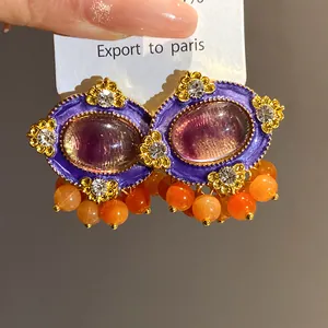 Macro view of vintage palace style purple resin earrings with orange bead tassels