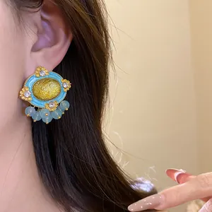 Close-up view of vintage court style oval resin stud earrings with gold filigree on model's ear