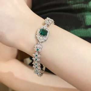 Elegant silver bracelet featuring square emerald-green zircons on a model's wrist