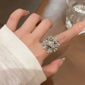 Detailansicht eines silbernen Vintage-Blumen-Cluster-Rings an einem Finger mit weißem Ärmel