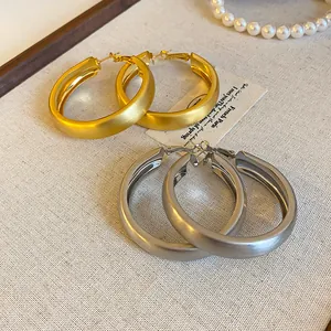 Macro view of brushed gold and silver hoop earrings on textured fabric