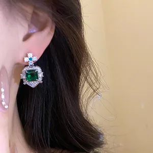Detailed close-up view of vintage square green zircon earrings worn by a model with hair