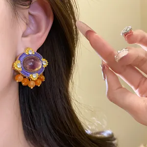 Detailed view of vintage palace style oval stud earring with purple resin and orange beads