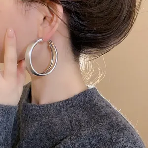 High-quality close-up of minimalist brushed silver large hoop earrings worn by a model