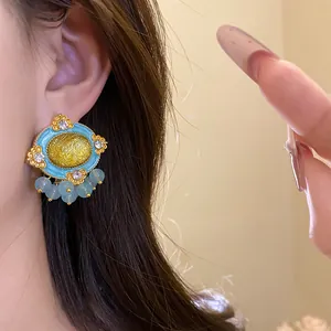 Close-up view of vintage court-style resin oval stud earrings with sparkling rhinestones
