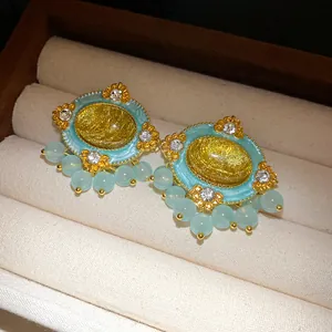 Close-up detail of vintage court-style oval earrings with blue resin and rhinestones.