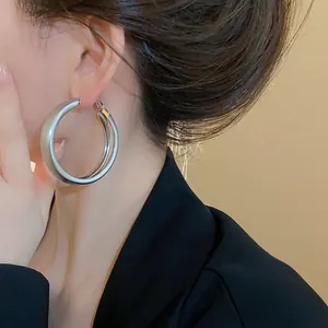 Detailed close-up of minimalist brushed silver hoop earrings worn on a model's ear
