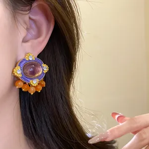 Close-up of vintage purple resin stud earrings with orange beads and sparkling crystals