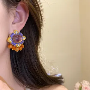 Macro view of vintage palace style earrings featuring purple resin and orange beads