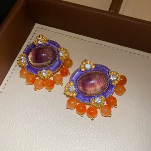 Detailed view of vintage purple resin earrings with oval center stone and orange beads.