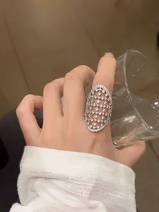 Detailansicht eines eleganten silberfarbenen Netzrings mit funkelnden Steinen an der Hand.