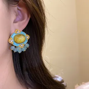 Close-up of vintage palace-style earrings with blue and yellow resin detail