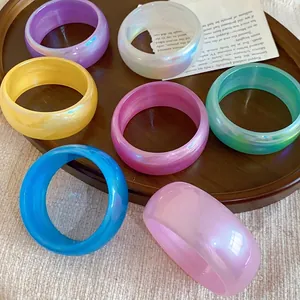 Juego de elegantes brazaletes anchos transparentes irisados con acabado perlado en bandeja