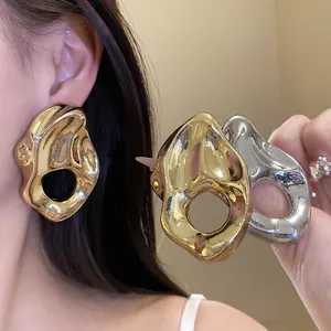 Vista detallada de pendientes metálicos irregulares en acabados oro y plata brillante