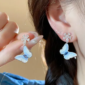 Detailed view of elegant silver zircon butterfly flower earrings on model ear and hand