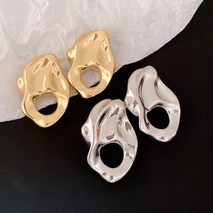 Primer plano de pendientes metálicos dorados y plateados con diseño plisado e irregular.