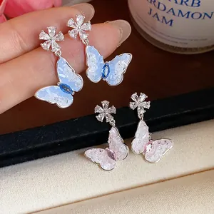 Detailed view of silver needle butterfly earrings with blue and pink zircon crystals.