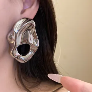 Primer plano de pendientes de metal plateado con diseño arrugado e irregular