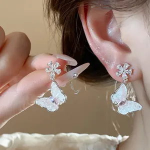 Detailed macro shot of elegant zircon flower earrings with a dangling white butterfly
