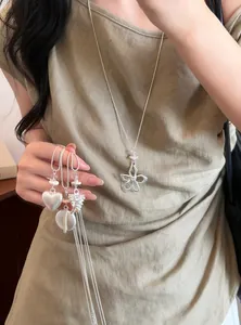 Détail d'un collier de perles argentées de style coréen avec pendentif en fleur sur modèle.