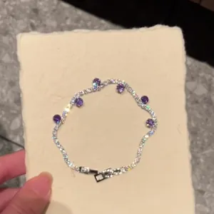 Detailed close-up of a silver-toned zircon tennis bracelet with purple round stones.