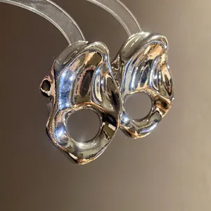 Primer plano que muestra la textura de metal arrugado y el diseño hueco de los pendientes.