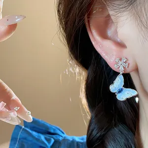 Close-up of elegant silver needle zircon butterfly flower stud earrings worn on ear