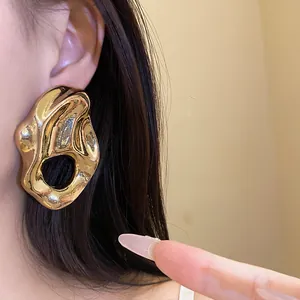 Primer plano de pendientes irregulares de metal dorado con textura arrugada