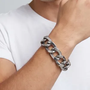 Primer plano de una pulsera de eslabones cubanos de acero inoxidable en una muñeca masculina.