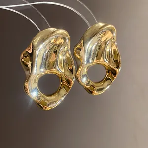 Primer plano detallado de pendientes huecos plisados dorados con textura metálica moderna