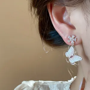 Detailed macro shot of zircon butterfly flower drop earring worn on an ear