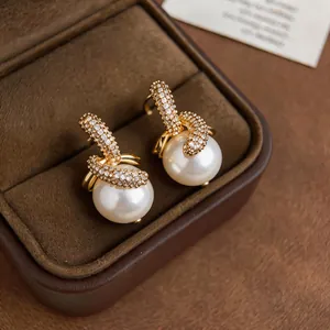 Nahaufnahme eleganter 18K vergoldeter Zirkon- und Perlenohrstecker in einer Box