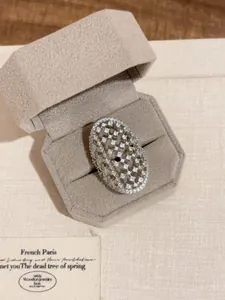 Nahaufnahme eines Vintage-Silberfarbenen hohlen breiten Rings mit Kristallen in grauer Box