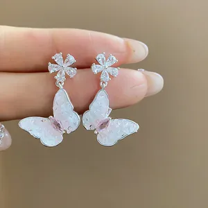Close-up detail of butterfly earrings with zirconia flower studs and iridescent pink wings