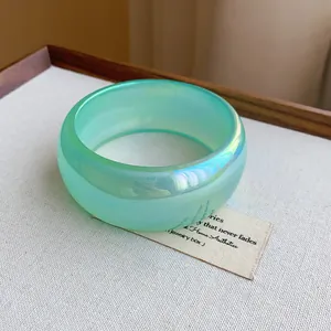Primer plano detallado de un brazalete ancho verde translúcido con efecto iridiscente