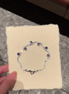 Macro detail of elegant zircon tennis bracelet featuring round purple accent stones