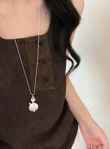Collier de perles argentées avec pendentif cœur et franges sur un joli haut en lin