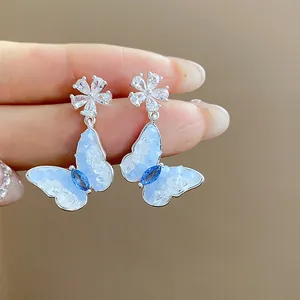 Detailed view of silver butterfly earrings with sparkling blue zircon petals