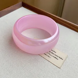 Detalle macro del brazalete ancho rosa transparente iridiscente en fondo estético