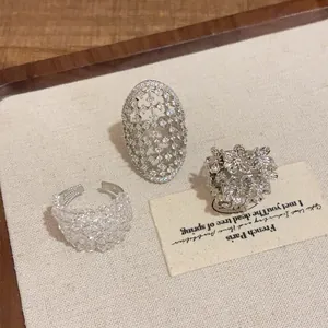 Nahaufnahme von drei silberfarbenen Ringen mit Gitter- und Blumenmustern im Vintage-Stil